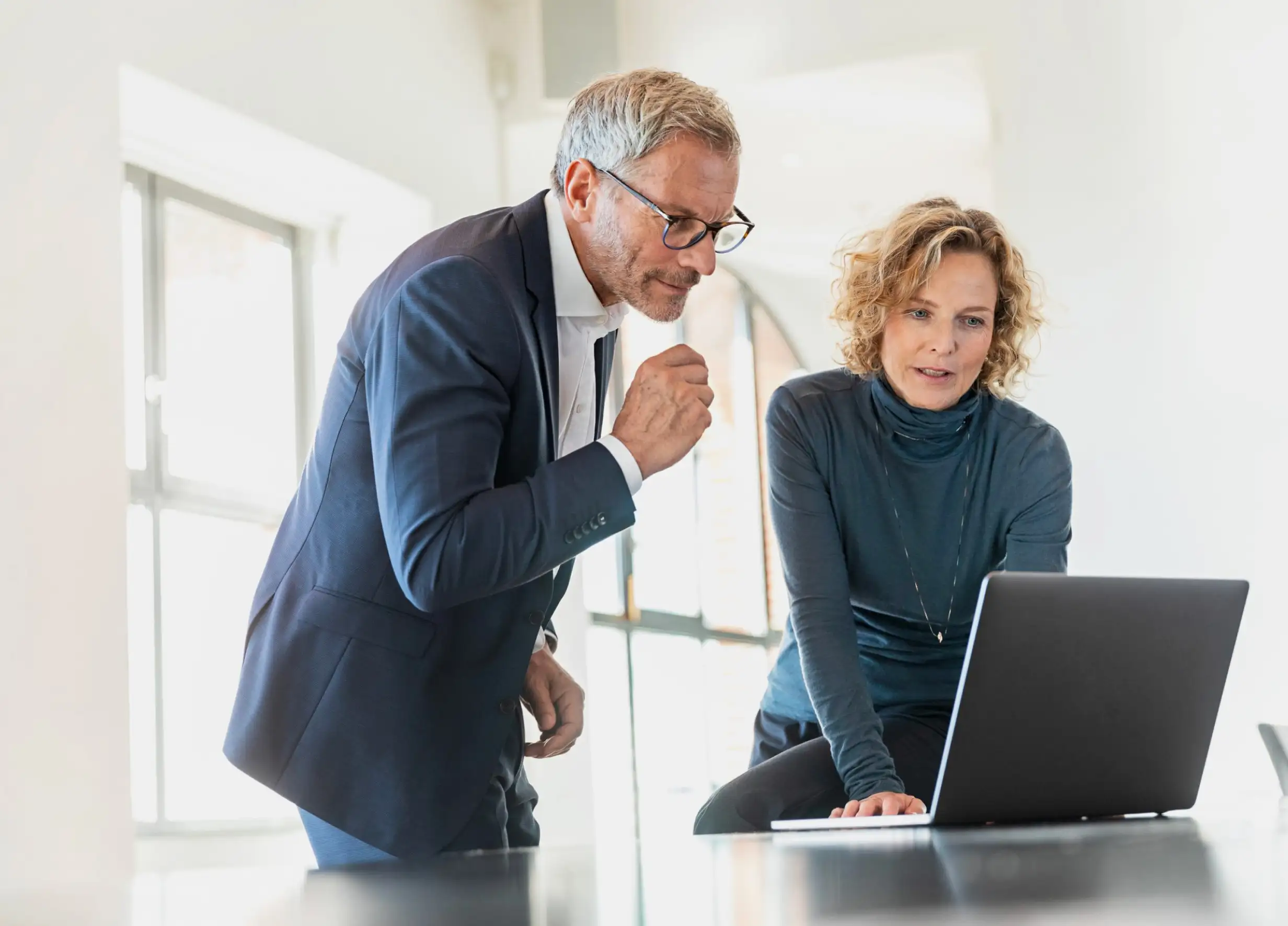 Woman showing man data on a laptop